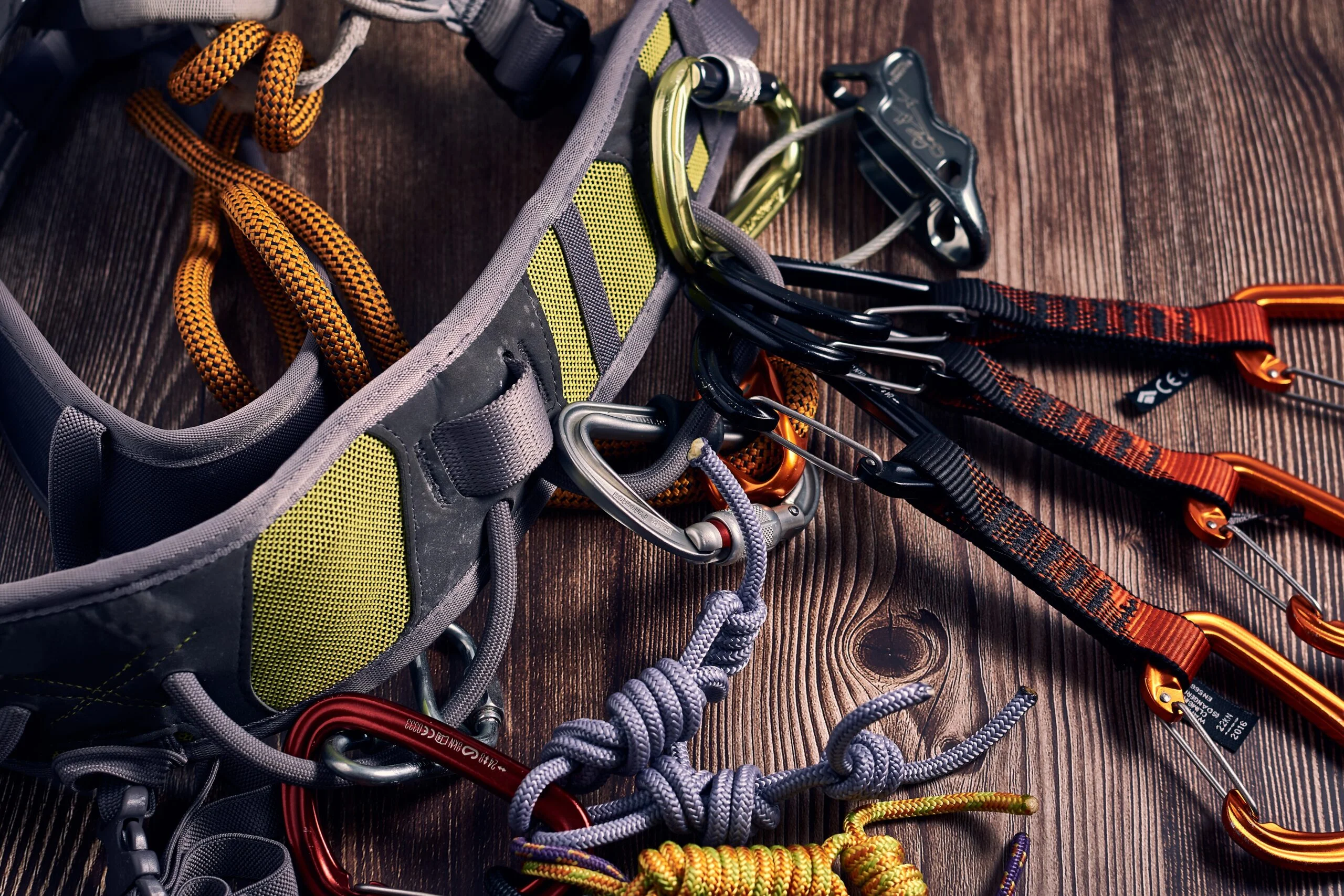closeup shot many colorful climbing carabiners knots wooden surface scaled