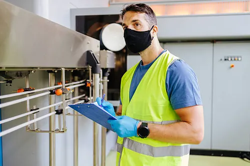 technician inspecting industrial machinery wearing protective gear